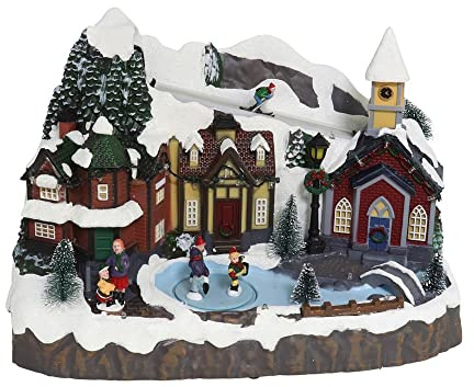 Generico Villaggio Città del Natale innevato con Pista di Pattinaggio e Pattinatori in Movimento, Paesaggio con Luci LED e Musica Scenario Natalizio Parco Giochi Carillon 35x25x23cm